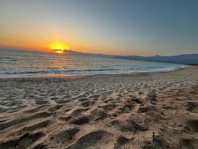 a beach with the sun setting over the ocean at Propriano Chalet near Sandy Beaches in Propriano