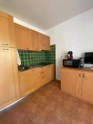 a kitchen with wooden cabinets and a tile floor at Casa Emma les pieds dans l'eau in San-Nicolao