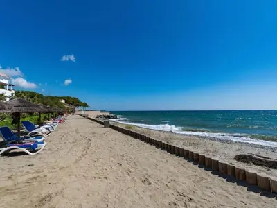 a beach with chairs and umbrellas and the ocean at Casa Emma les pieds dans l'eau in San-Nicolao
