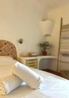 a rolled up towel sitting on a bed at Hôtel Palombaggia in Porto-Vecchio
