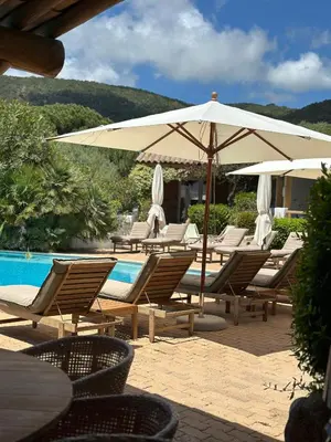 a group of chairs and an umbrella next to a pool at Hôtel Palombaggia in Porto-Vecchio