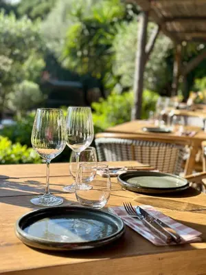 a wooden table with two wine glasses on it at Hôtel Palombaggia in Porto-Vecchio