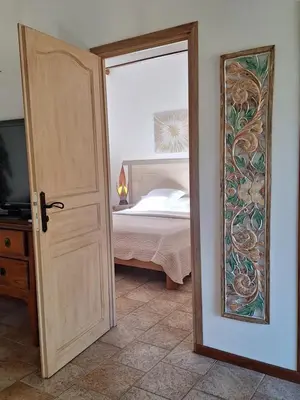 a door to a bedroom with a bed and a mirror at Gîte Acellu in Bonifacio