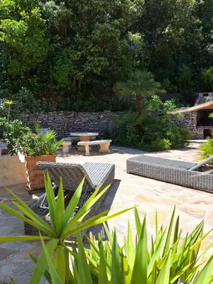 a patio with benches and a picnic table in a garden at Gîte Acellu in Bonifacio