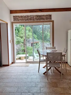 a dining room with a table and chairs and a large window at Gîte Acellu in Bonifacio