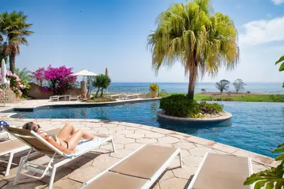 a woman laying in a chair next to a swimming pool at La Solenzara hôtel - 3 Etoiles Supérieur - Appartement & SPA in Sari Solenzara