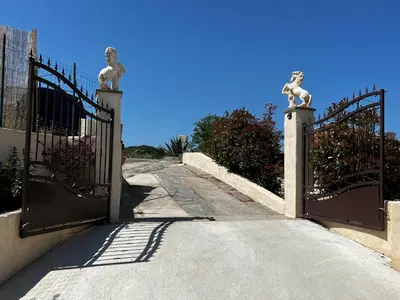 an entrance to a building with a gate with statues at Villa MonteCristo, clim, piscine privée, 300m. mer in Talasani