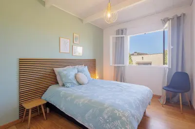 a bedroom with a bed and a blue chair and a window at Villa MonteCristo, clim, piscine privée, 300m. mer in Talasani