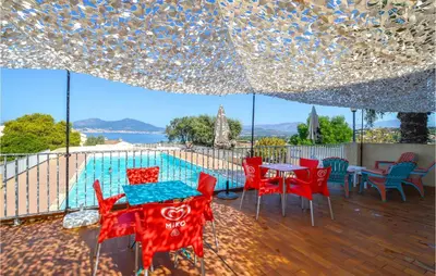 a patio with red chairs and tables under a tent at 2 Bedroom Cozy Home In Porticcio in Porticcio