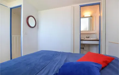 a bedroom with a blue bed with a red pillow at 2 Bedroom Cozy Home In Porticcio in Porticcio