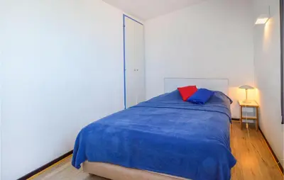 a bedroom with a blue bed with a red pillow at 2 Bedroom Cozy Home In Porticcio in Porticcio