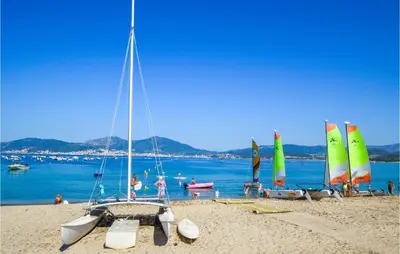 a group of sailboats on a beach with people on it at 2 Bedroom Cozy Home In Porticcio in Porticcio