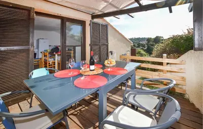 a blue table with red plates on a deck with chairs at 2 Bedroom Cozy Home In Porticcio in Porticcio