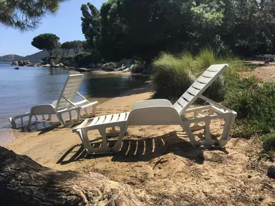 two white chairs sitting on a beach next to the water at Résidence les pieds dans l'eau in Porto-Vecchio