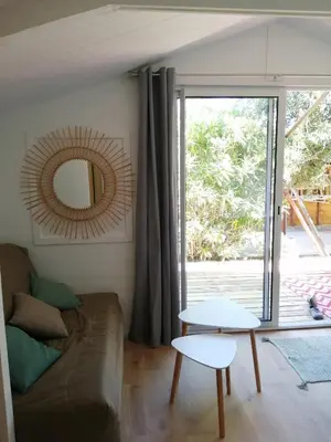 a living room with a couch and a mirror at Les chalets de Palavesa in Porto-Vecchio