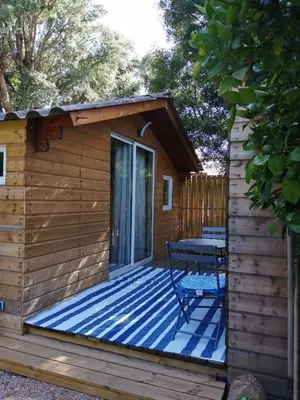 a wooden cabin with a table on a deck at Les chalets de Palavesa in Porto-Vecchio