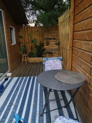 a patio with a table and chairs on a deck at Les chalets de Palavesa in Porto-Vecchio