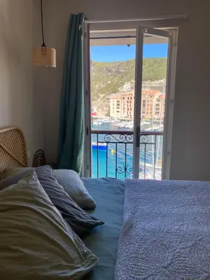 a bedroom with a bed with a view of the ocean at Appartement vue sur le port - Chez Carlu in Bonifacio