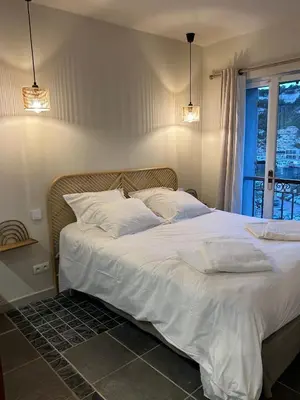 a bedroom with a bed with white sheets and a window at Appartement vue sur le port - Chez Carlu in Bonifacio
