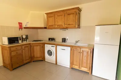 a kitchen with wooden cabinets and a washer and dryer at Residence Mare e Sole in Taglio-Isolaccio