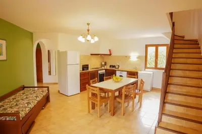 a kitchen with a table and a white refrigerator at Residence Mare e Sole in Taglio-Isolaccio