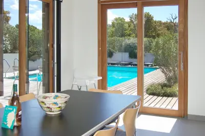 a dining room with a table and a view of a pool at Villa Coucou Les Amis in Sainte-Lucie de Porto-Vecchio