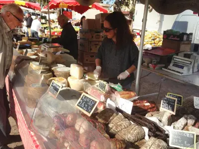 a woman standing in front of a market selling food at Villa Coucou Les Amis in Sainte-Lucie de Porto-Vecchio