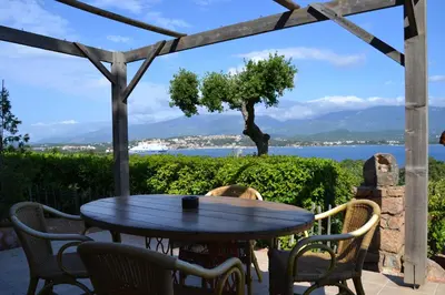 a table and chairs on a patio with a view of the water at Résidence Alt'aria in Porto-Vecchio