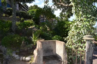 a garden with a stone fireplace next to a fence at Résidence Alt'aria in Porto-Vecchio