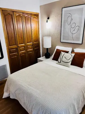 a bedroom with a white bed with a wooden cabinet at Charmant Appartement centre-ville in Ajaccio