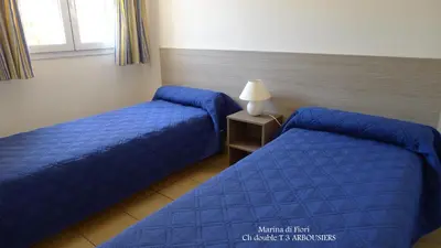 two beds in a hotel room with blue sheets at Marina di fiori in Propriano
