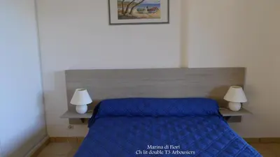 a bedroom with a blue bed with two lamps at Marina di fiori in Propriano