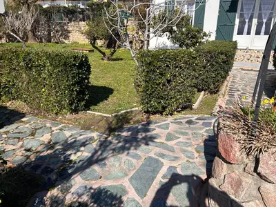 a garden with bushes and a stone walkway at Petite villa le clan in Ajaccio