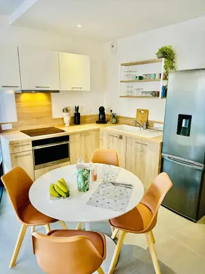 a kitchen with a table and chairs and a refrigerator at DOMAINE D'ARCA, T2 JARDIN PRIVE/PISCINE/TENNIS in Porto-Vecchio