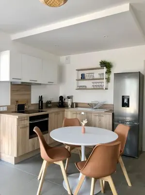 a kitchen with a table and chairs in a kitchen at DOMAINE D'ARCA, T2 JARDIN PRIVE/PISCINE/TENNIS in Porto-Vecchio