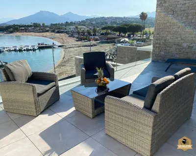 a patio with chairs and a table and a view of the water at Le Galatée Porticcio in Porticcio