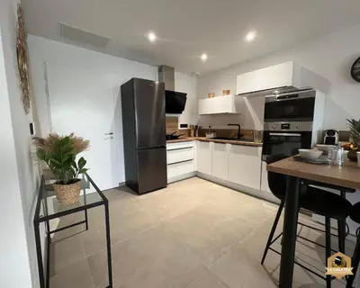 a kitchen with a stainless steel refrigerator and a table at Le Galatée Porticcio in Porticcio