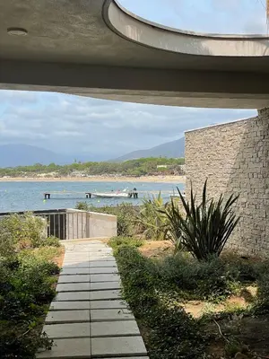 a walkway next to a beach with a boat in the water at Le Galatée Porticcio in Porticcio