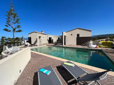 a swimming pool with chairs and a house at VILLA A SCOPA 14 VUE PANORAMIQUE MER * in Pietrosella