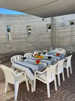 a long table with white chairs and a blue table cloth at VILLA A SCOPA 14 VUE PANORAMIQUE MER * in Pietrosella