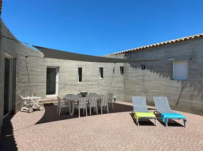 a patio with a table and chairs and a building at VILLA A SCOPA 14 VUE PANORAMIQUE MER * in Pietrosella