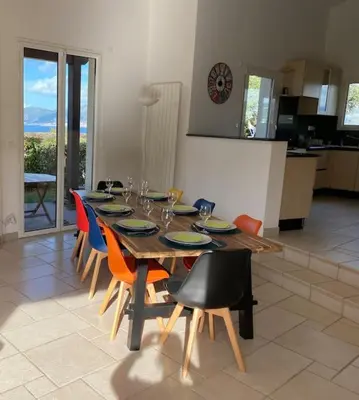 a wooden table with chairs and a dining room at VILLA A SCOPA 14 VUE PANORAMIQUE MER * in Pietrosella
