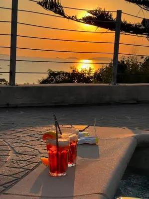 two drinks sitting on a ledge with the sunset in the background at VILLA A SCOPA 14 VUE PANORAMIQUE MER * in Pietrosella