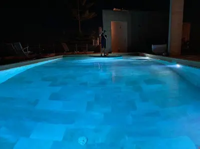 a large blue swimming pool at night at VILLA A SCOPA 14 VUE PANORAMIQUE MER * in Pietrosella
