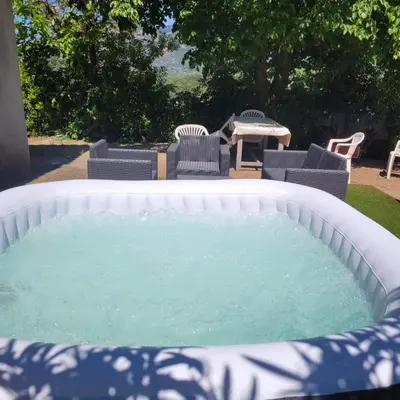 a large hot tub with chairs and a table at Bas de villa F3 proche Ajaccio in Cuttoli-Corticchiato