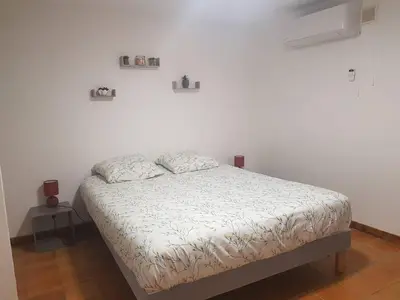 a bed in a room with a white wall at Bas de villa F3 proche Ajaccio in Cuttoli-Corticchiato