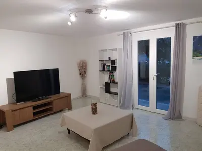 a living room with a television and a table at Bas de villa F3 proche Ajaccio in Cuttoli-Corticchiato