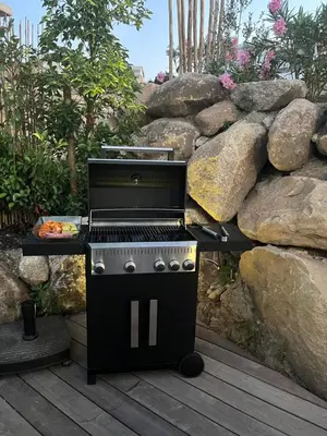 a barbecue grill sitting on a deck next to a rock wall at Villa Kalinas Corse 4 étoiles in Sari Solenzara