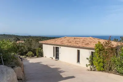 a white building with a tile roof next to a road at Villa Kalinas Corse 4 étoiles in Sari Solenzara