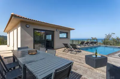 a patio with a table and chairs and a pool at Villa Kalinas Corse 4 étoiles in Sari Solenzara